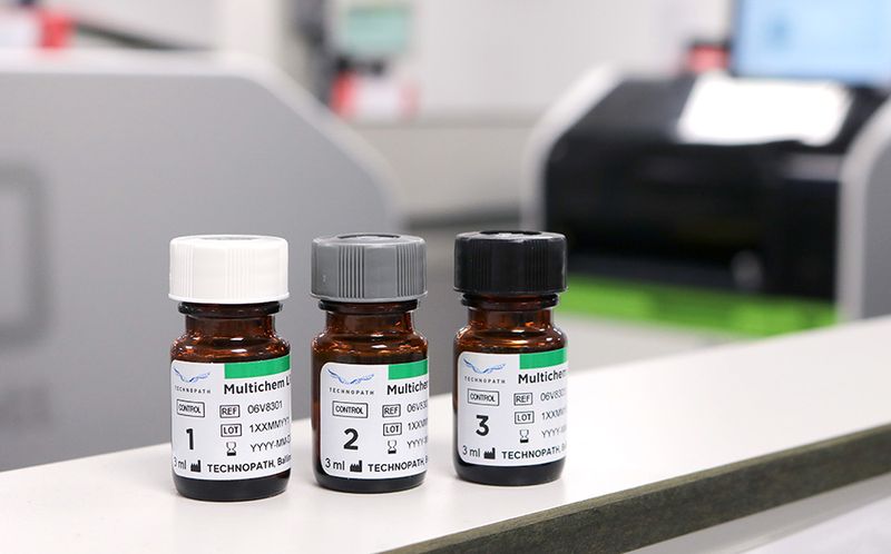 Multichem LPS vials sitting on a laboratory bench with  Abbott Alinity c instruemnt in background
